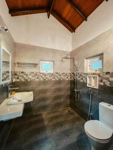 a bathroom with a toilet and a sink and a shower at Cozy Nook Cottage in Tangalle