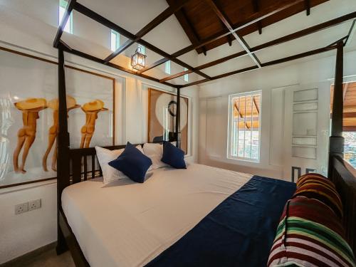 a bedroom with a large bed with blue pillows at Cozy Nook Cottage in Tangalle