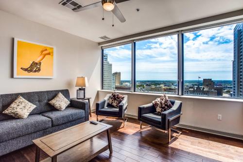 a living room with a couch and chairs and large windows at CozySuites at LTV in Dallas