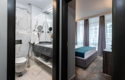 a bathroom with a tub and a sink and a toilet at Best Western PLUS Premium Inn in Sunny Beach