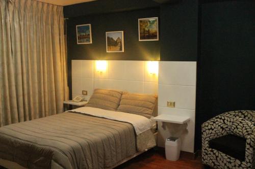 a bedroom with a bed and a chair in it at Hotel Venecia in Huánuco