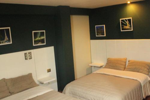 a bedroom with two beds and pictures on the wall at Hotel Venecia in Huánuco