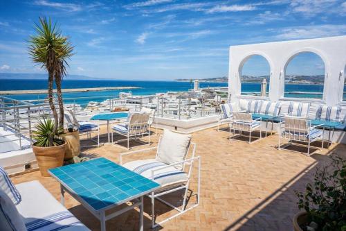 a patio with chairs and tables and the ocean at Le balcon de tanger in Tangier