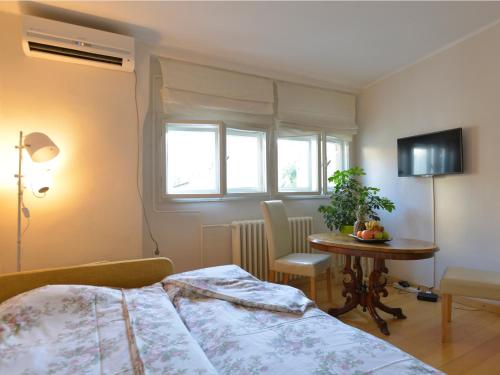 a bedroom with a bed and a table and a window at Downtown dell Arte in Novi Sad