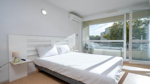 a bedroom with a white bed and a large window at Le St Clair N208 ST2 in Agde