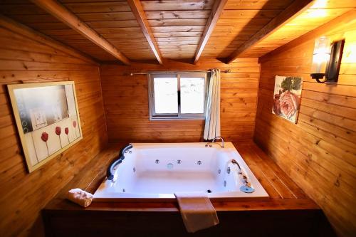 a large bath tub in a room with wooden walls at נופים בלבן - בקתה עם בריכה פרטית ואמבט ספא in Moshav Ramot