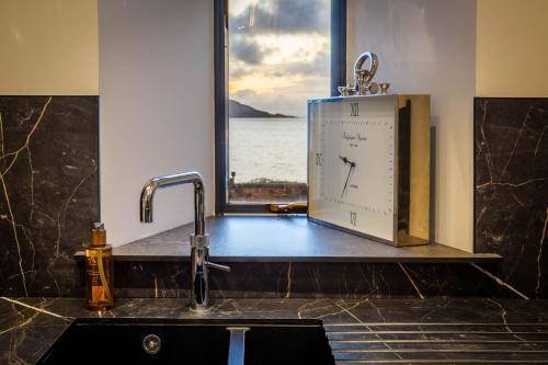 a clock sitting on a counter in front of a window at Arran Shores Luxury Shorefront Suite 1 in Lamlash