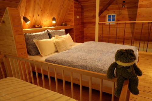 a teddy bear sitting on a bed in a cabin at Baglyos Vendégház Kulcs in Kulcs