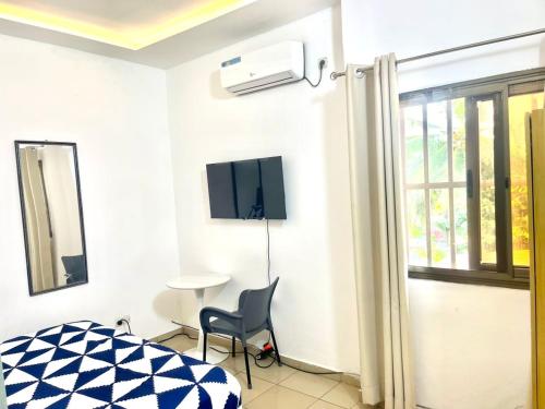 a bedroom with a bed and a chair and a window at HEBERTOGO Casablanca in Lomé