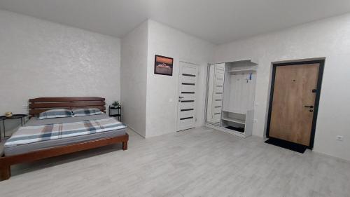 a white bedroom with a bed and a door at Уютная квартира в Одессе in Odesa