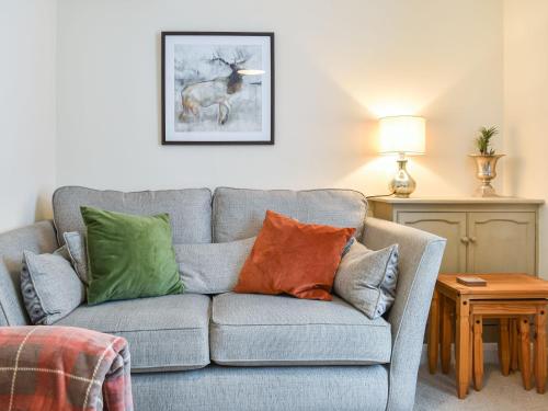 a living room with a gray couch with colorful pillows at Pear Tree Cottage in Enderby