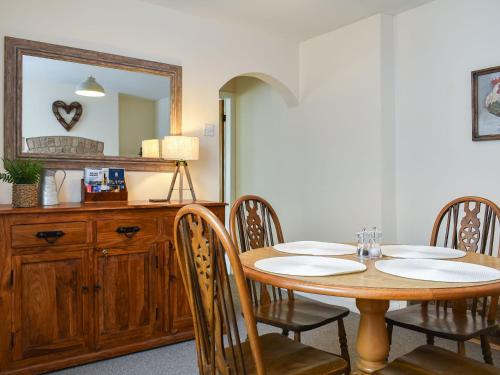 a dining room with a table and a mirror at Pear Tree Cottage in Enderby