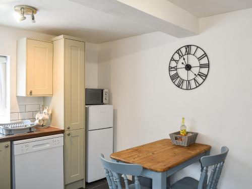 a kitchen with a table and a clock on the wall at Pear Tree Cottage in Enderby