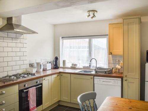 a kitchen with yellow cabinets and a sink and a window at Pear Tree Cottage in Enderby