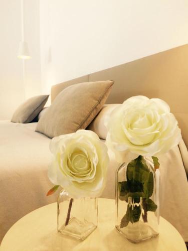 two roses in vases on a table next to a bed at Apartamentos La Estación M&S in Albacete