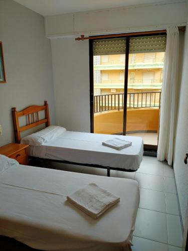 a hotel room with two beds and a window at Tamaris Playa Solo Familias Serviplaya in Playa de Xeraco