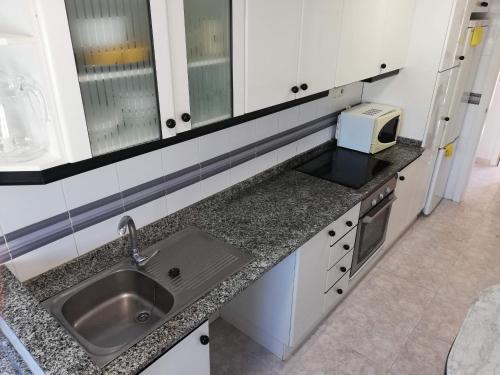 a kitchen with a sink and a microwave at Oasis Solo Familias Serviplaya in Playa de Xeraco