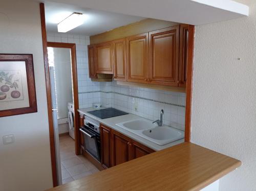 a kitchen with wooden cabinets and a sink and a stove at Deltamar Solo Familias Serviplaya in Xeraco