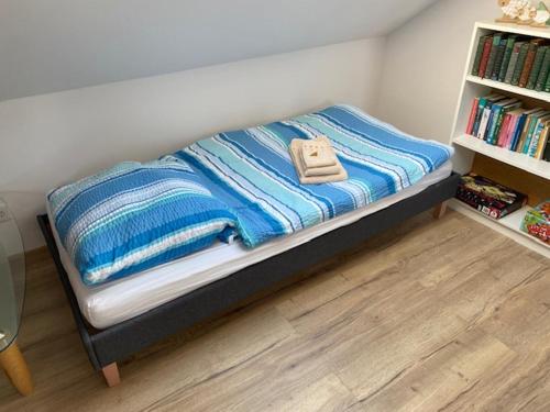 a bed with blue and white blankets and a book shelf at Lieblingsplatz an der Lahn in Weinbach
