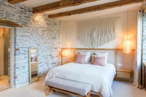 a bedroom with a large bed and a stone wall at La Maison Brevan in Châteaulin