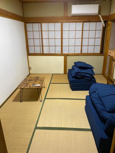 a room with two beds and a table in it at 釣り宿yasakabase guesthouse in Sado