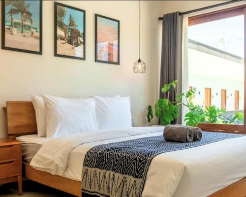 a bedroom with a bed and a large window at Lay Day Hostel Uluwatu in Uluwatu
