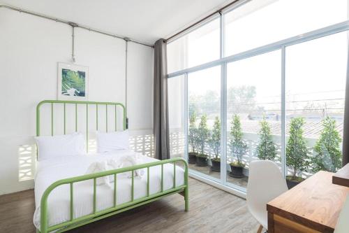 a bedroom with a green bed and a large window at Memmoth Cafe & Hostel in Lampang in Lampang