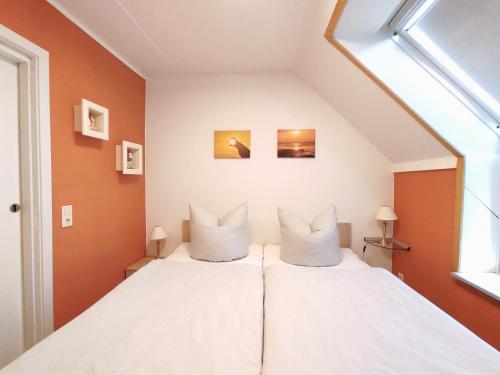 a bedroom with a white bed with orange walls at Ostseeliebe in Kirchdorf