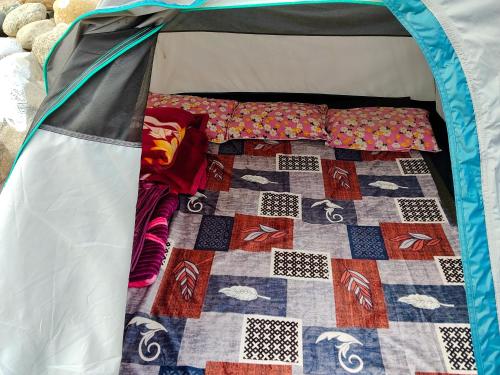 a bed in a tent with a quilt on it at Rickson Riverside Campsite in Dawki