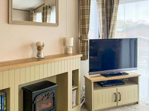 a living room with a television and a fireplace at Lodge 58 in Aviemore