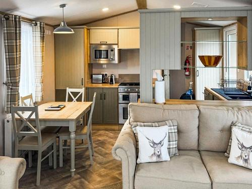 a living room and kitchen with a couch and a table at Lodge 58 in Aviemore