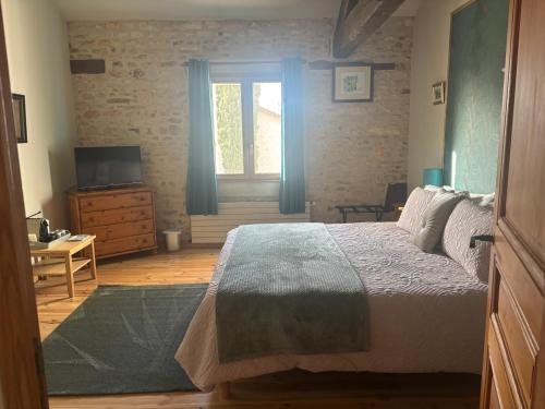 une chambre avec un lit, une télévision et une fenêtre dans l'établissement La Grange, à Blanzay