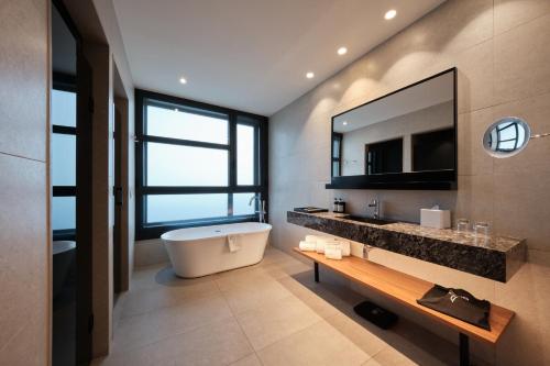 a bathroom with a tub and a sink and a mirror at Catalonia Barcelona Plaza in Barcelona