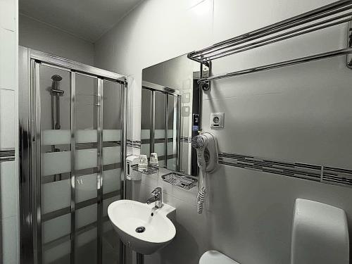 a small bathroom with a sink and a shower at Hostal Doña Isabel in Majadahonda