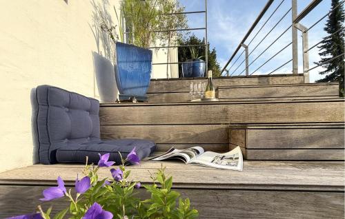 a chair sitting on a porch with a book and flowers at 2 Bedroom Nice Apartment In Vejle Øst in Bredballe