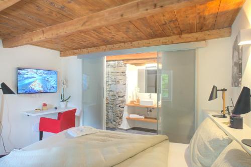 a bedroom with a bed and a bathroom with a stone wall at MyVerzasca Boutique Hotel in Brione