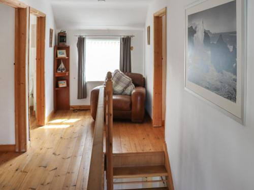 a living room with a leather couch and a window at Holly Cottage in Angle