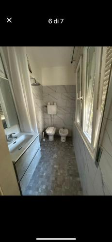 a bathroom with a toilet and a sink and a window at Hotel Bianca Vela in Rimini