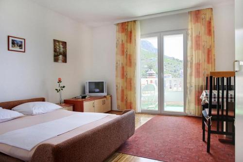 a bedroom with a bed and a tv and a window at Apartments Rose in Stanići