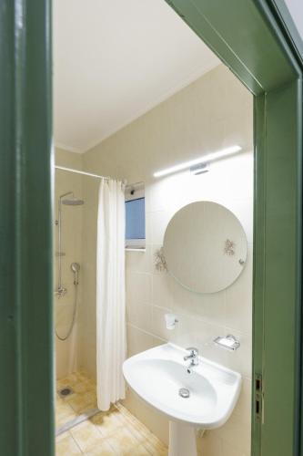 a bathroom with a sink and a shower and a mirror at Ilios Mare Hotel in Agia Marina Nea Kydonias