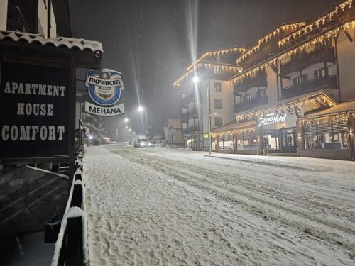 a snow covered street in front of a building at Private Suite at Comfort Bansko in Bansko