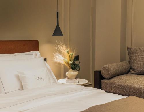a bedroom with a bed and a couch and a vase with flowers at Lenel Boutique Room - La Foresteria in Brescia