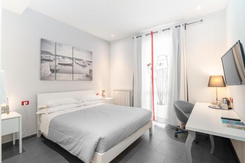 a white bedroom with a bed and a desk and a computer at Excelsior in Piombino