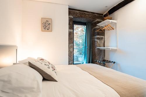 a bedroom with a white bed with a window at Villa Seara - Casas da Vinha in Celorico de Basto