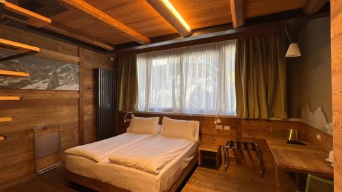 a bedroom with a bed and a desk and a window at MH Olen Boutique Hotel in Alagna Valsesia