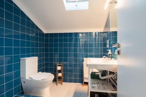 a blue tiled bathroom with a toilet and a sink at Villa Seara - Casas da Vinha in Celorico de Basto