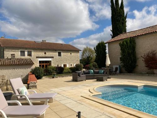 une terrasse avec piscine et chaises longues et une maison dans l'établissement La Grange, à Blanzay