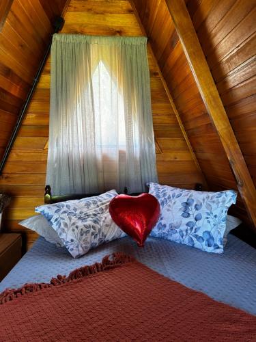 a red heart pillow sitting on a bed in a attic at Chalé nascer do sol in Massaranduba
