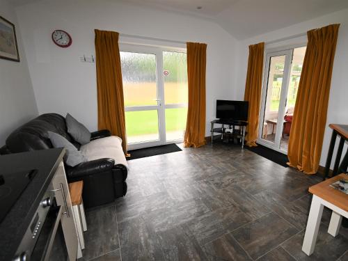 a living room with a couch and a television at Orchard Farm Cottage in Barnby