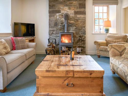 a living room with a wooden coffee table and a fireplace at Weavers Cottage in Kenmore
